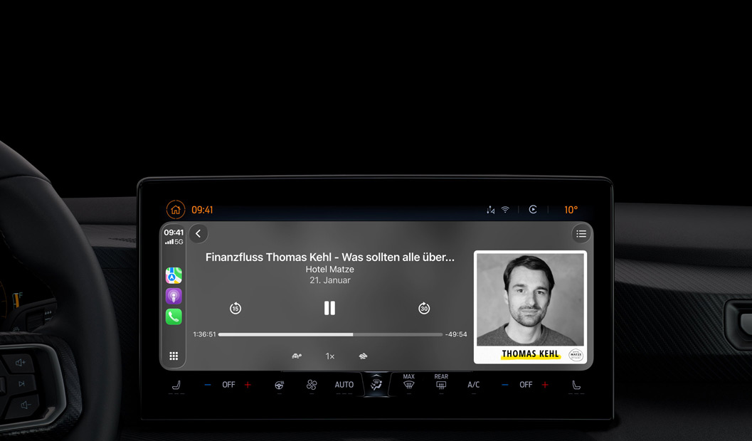 Ein Autointerieur, das Display der Mittelkonsole zeigt Apple Podcasts, die über CarPlay wiedergegeben werden, es läuft der Podcast „The Spark of Life“ von Radiolab, die Wiedergabesteuerung umfasst Zurück, Pausieren und Vorwärts.