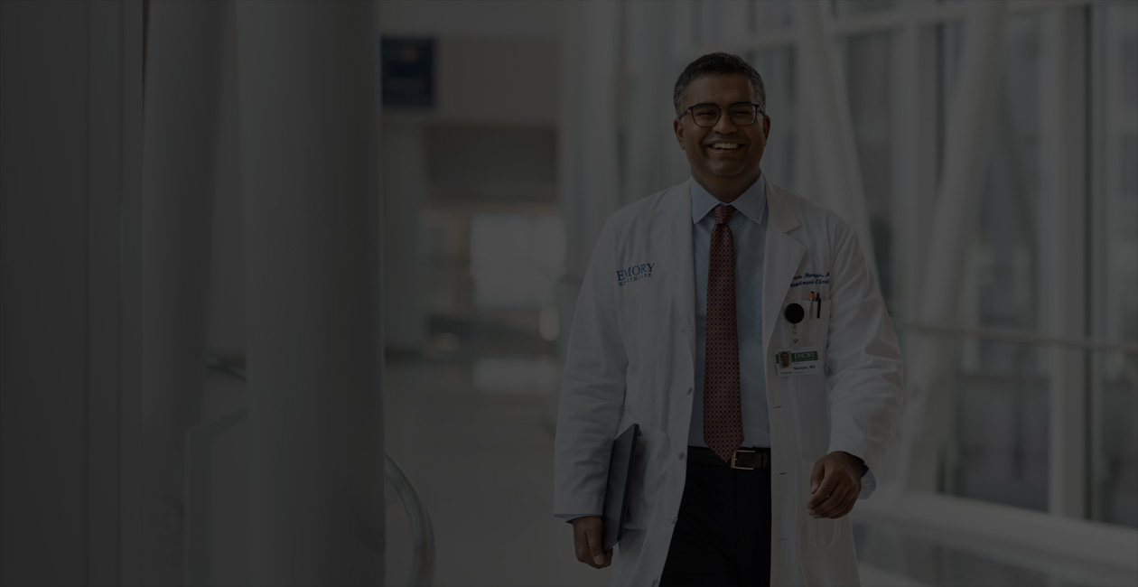 Un médecin qui marche en tenant un MacBook sous son bras droit.