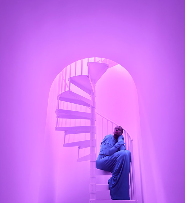 Close de uma mulher sentada em uma escada espiral para demonstrar os recursos fotográficos em baixa iluminação do sistema de câmera Pro