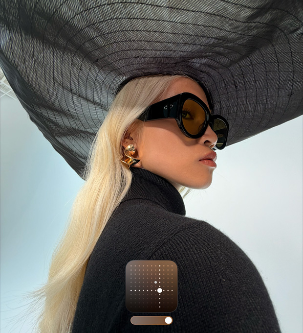 Retrato de uma mulher usando um chapéu preto de abas largas para demonstrar o Estilo Fotográfico Brilhante, que realça fotos tiradas em condições de baixa iluminação ou com o modo Noite ativado
