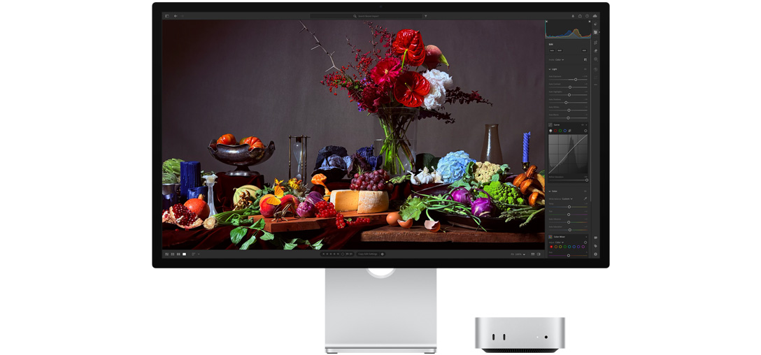 Visokokontrastna slika stola s raznim tanjurima s hranom i buketom ispred tamne pozadine, demonstrira kako True Tone prilagođava temperaturu boje.