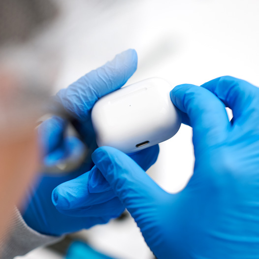 라텍스 장갑을 낀 두 손으로 AirPods 케이스를 잡고 있는 모습