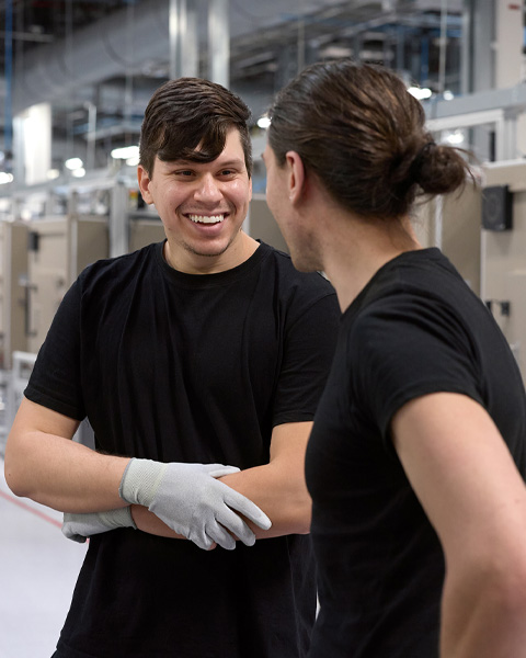 두 직원이 iMac 조립 창고에서 서로 이야기를 나누는 모습