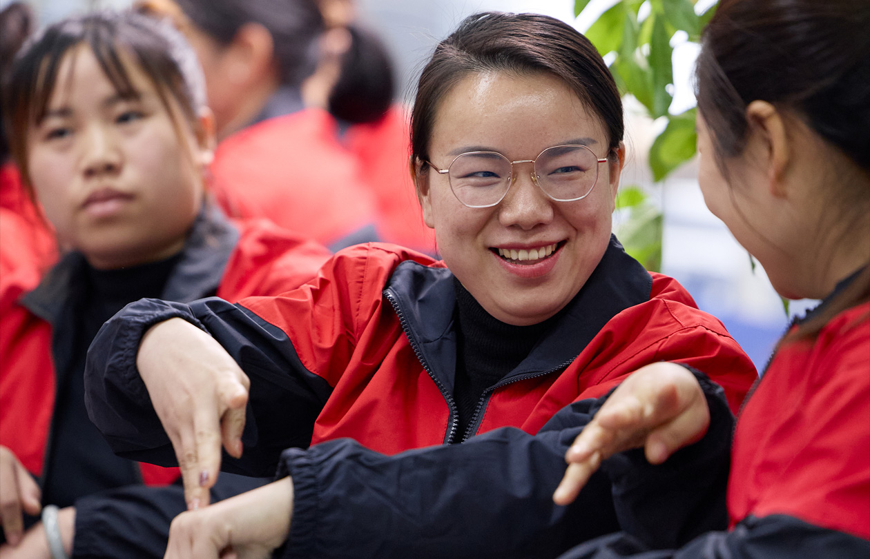앉아 있는 직원 세 명 중 한 명이 다른 직원에게 손짓으로 이야기하는 모습