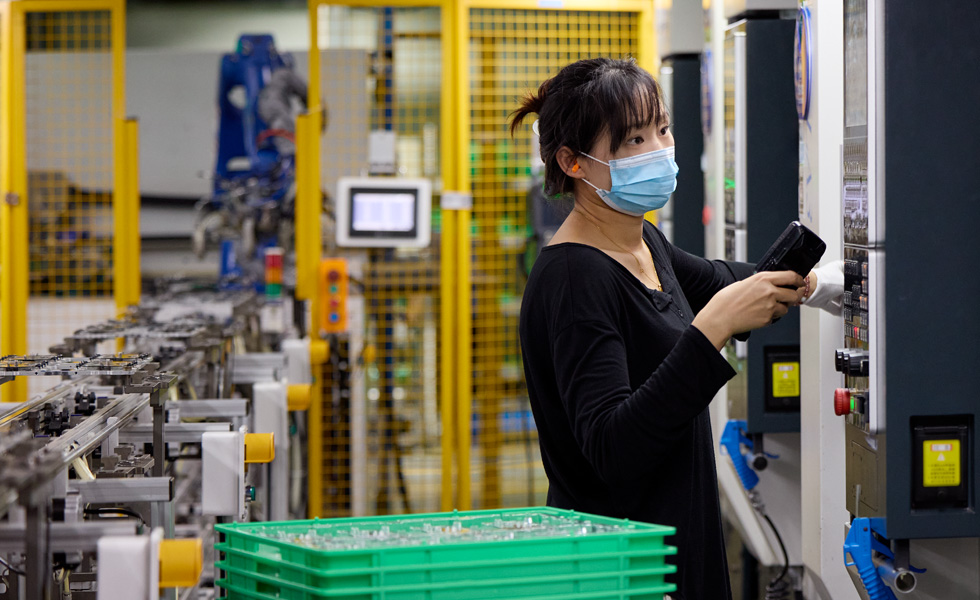 직원이 부품 제조 시설에서 기계를 조작하는 모습