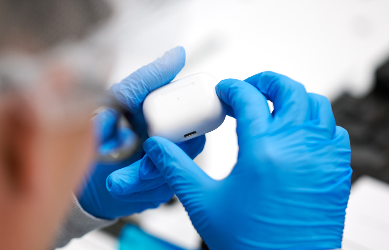 라텍스 장갑을 낀 두 손으로 AirPods 케이스를 잡고 있는 모습